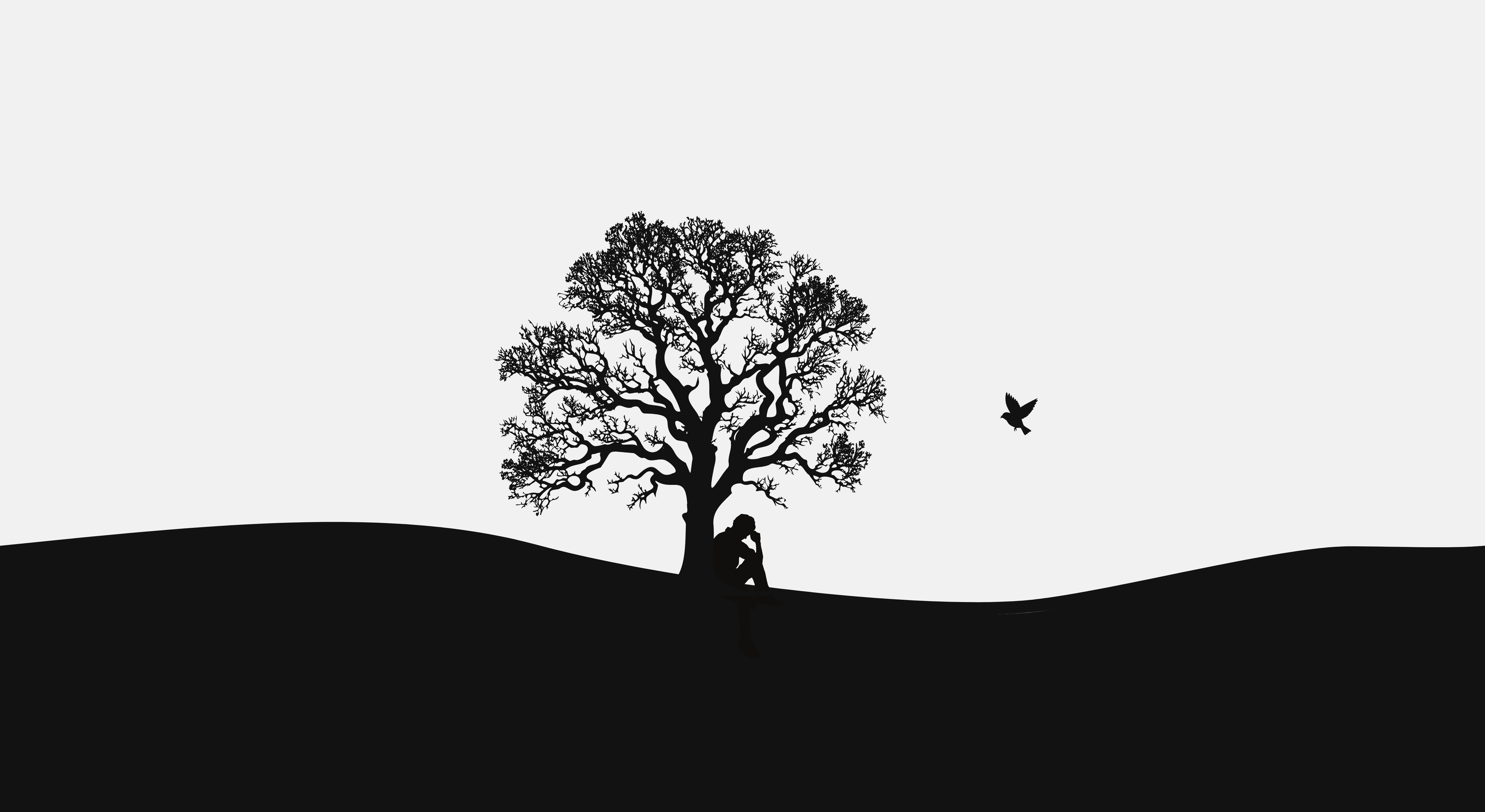 A man sitting against an oak tree with a bird nearby